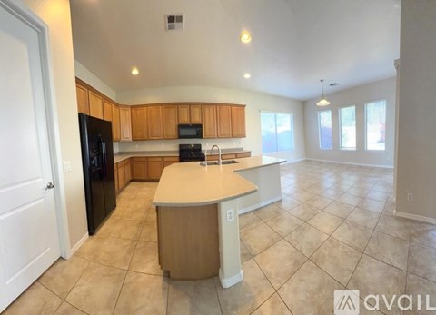 A kitchen with a black refrigerator, wooden cabinets, and a white island.