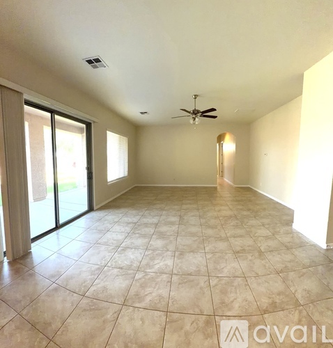 A spacious room with a ceiling fan and sliding glass doors.