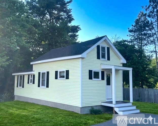 A small white house with a black roof and a porch.