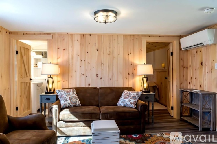 A living room with a brown couch and a wooden wall.