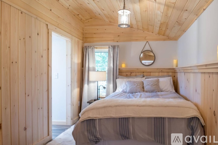 A bedroom with wooden walls and a bed with a white comforter.