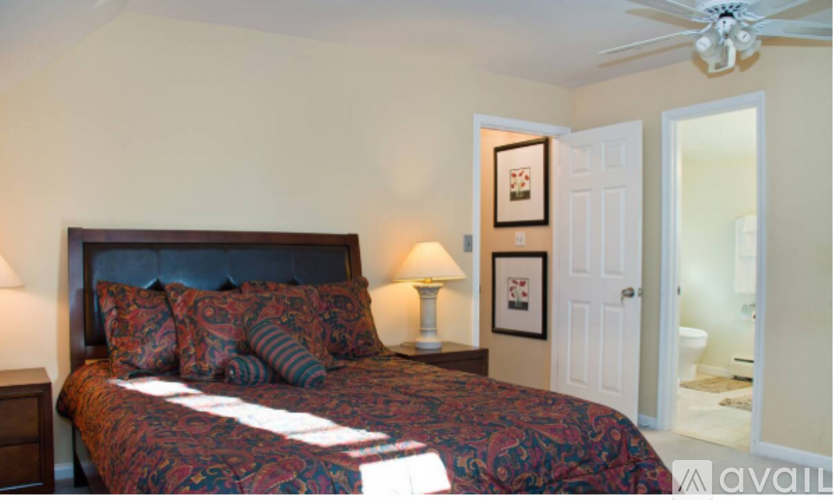 A bedroom with a bed, a ceiling fan, and a doorway leading to another room.