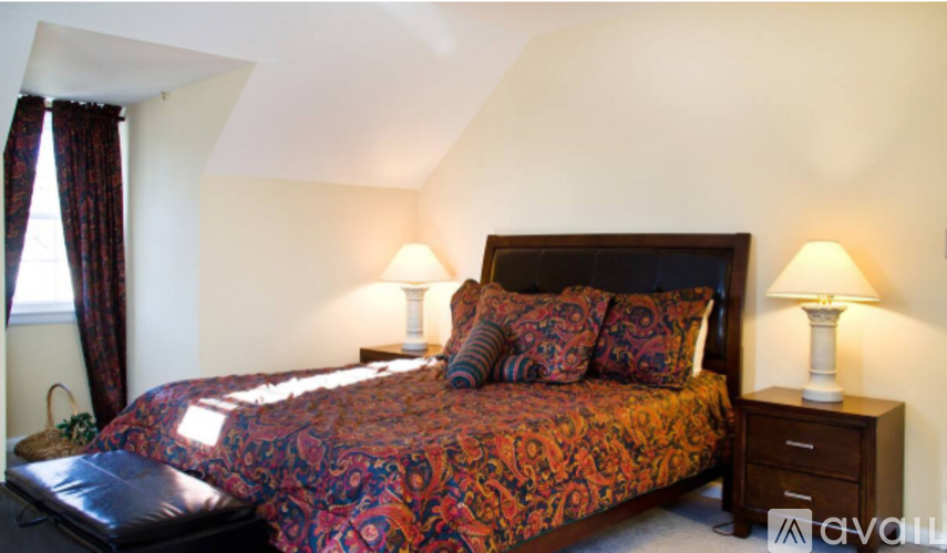 A bed with a red and black comforter sits next to two lamps.