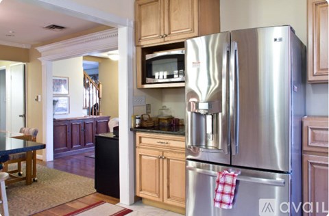 A kitchen with a stainless steel refrigerator and wooden cabinets.
