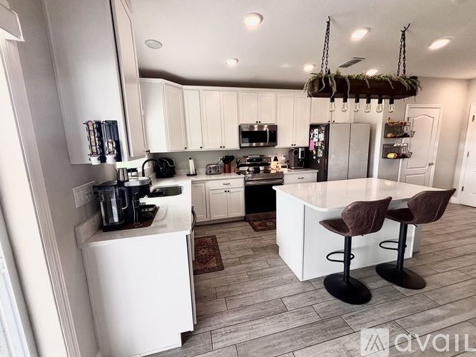A kitchen with white cabinets and a large island with two chairs.