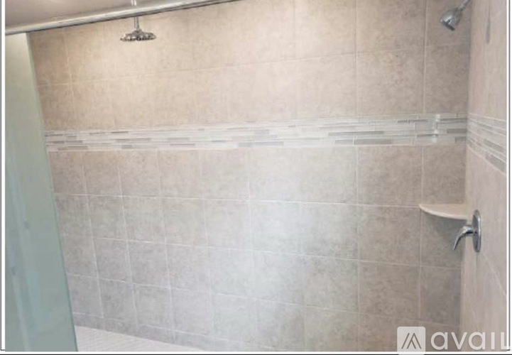 A shower area with a glass door and a wall of tiles.