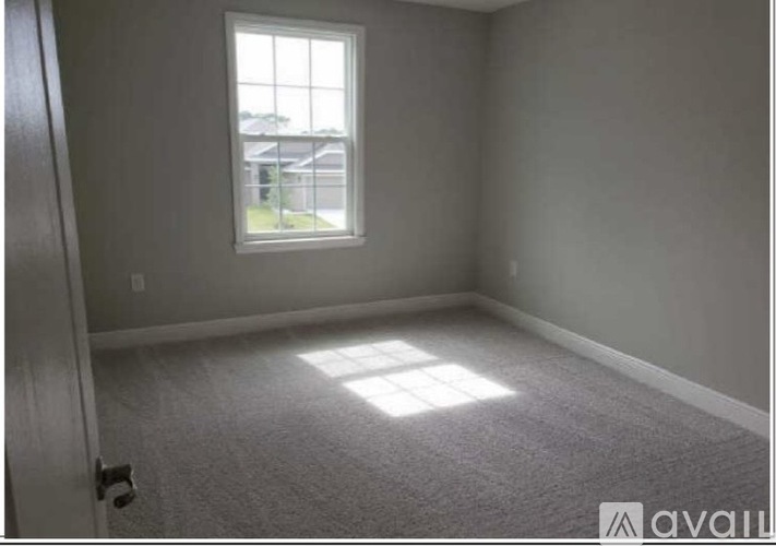 A room with a window and carpeted floor.