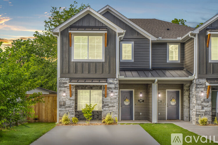 A modern house with a grey exterior and a stone wall entrance.