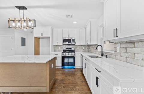 A modern kitchen with white cabinets and a wooden island.