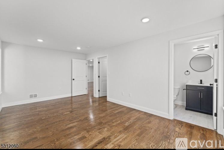 A room with wooden floors and white walls, with a door on the right side.