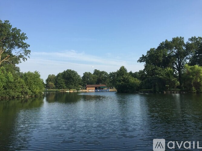 A calm lake surrounded by trees under a clear blue sky.