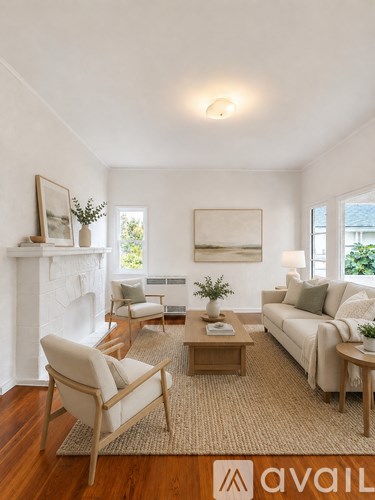A living room with a white fireplace, a couch, a chair, a coffee table, and a painting on the wall.