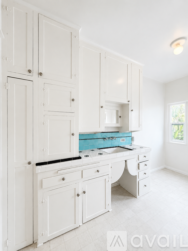 A kitchen with white cabinets and a blue box on the counter.