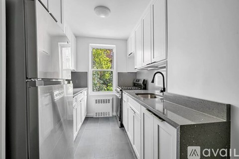 A kitchen with white cabinets and a window overlooking trees.