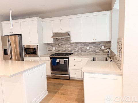 A kitchen with white cabinets and a stainless steel refrigerator.