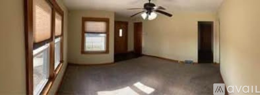 A room with a ceiling fan and a window overlooking a balcony.