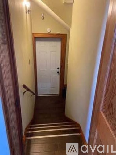 A hallway with a white door and striped tiles on the floor.