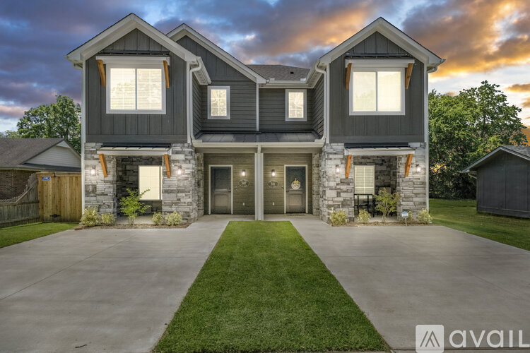 A modern house with a stone facade and a large front yard.