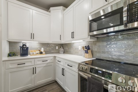 A kitchen with white cabinets and a black stove top oven.
