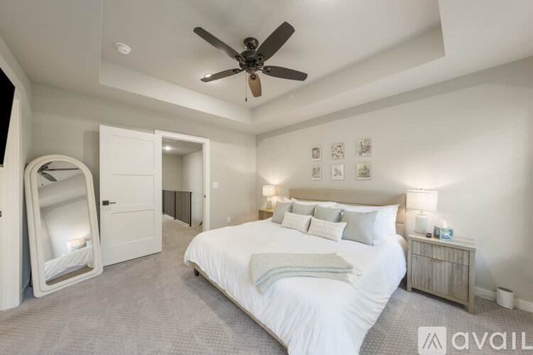 A bedroom with a large bed, a ceiling fan, and a nightstand with a lamp.