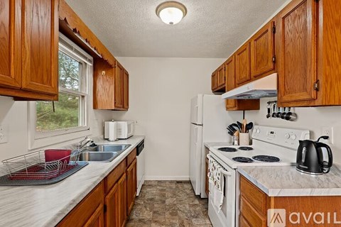 A kitchen with wooden cabinets and a white stove top oven.