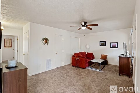 A living room with a red couch and a ceiling fan.