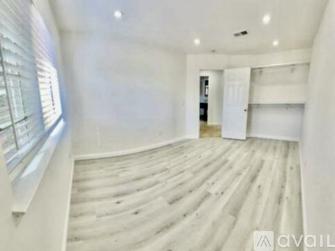 A spacious room with wooden flooring and white walls.