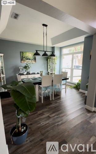 A dining room with a table set for four and a potted plant on the table.