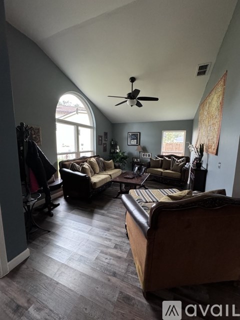 A living room with a brown couch and a ceiling fan.