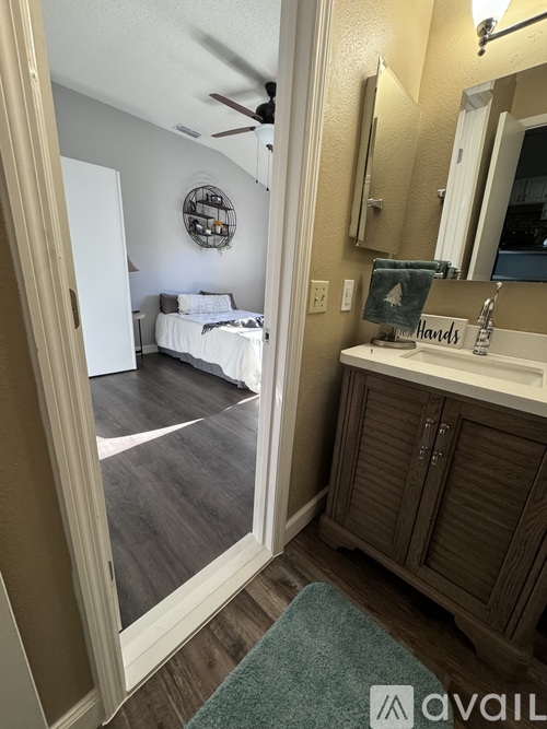 A bathroom with a mirror, sink, and a bedroom in the background.