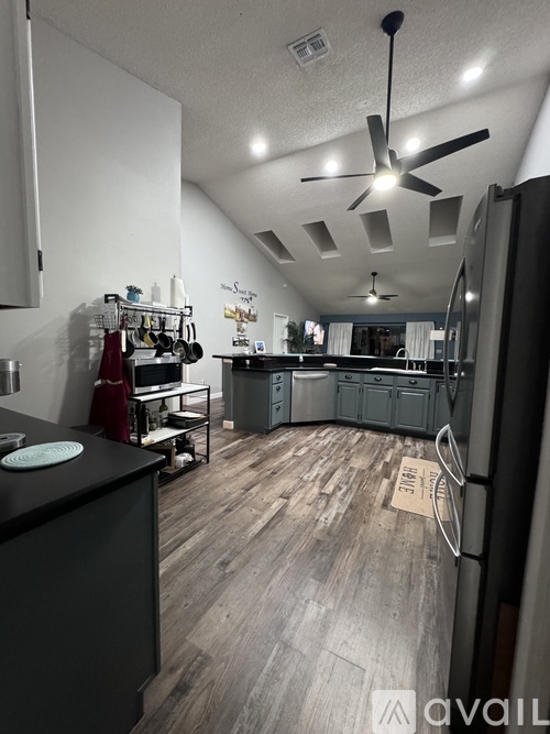 A kitchen with a black countertop and a ceiling fan.
