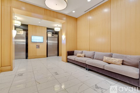 A modern living room with a grey couch and a television on the wall.