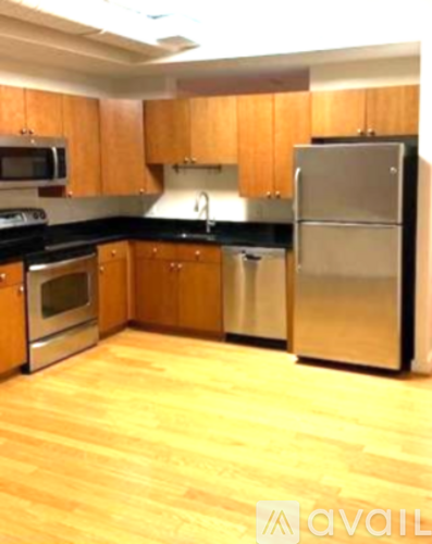 A kitchen with wooden cabinets and a stainless steel refrigerator.