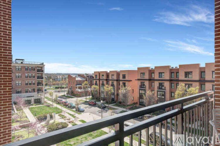 A view from a balcony overlooking a parking lot and buildings.