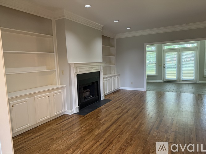 A living room with a fireplace and built-in shelves.