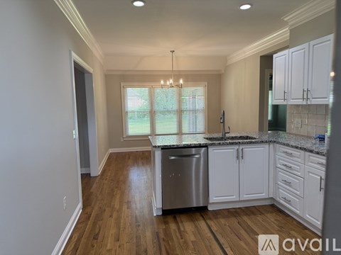 A kitchen with white cabinets and a wooden floor.