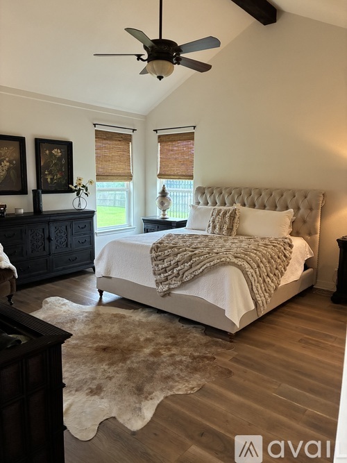 A bedroom with a large bed and a rug on the floor.