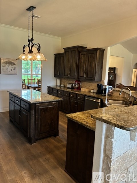 A kitchen with dark wood cabinets and a granite countertop.