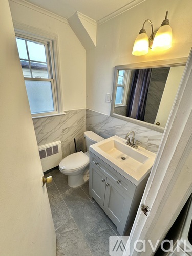 A bathroom with a toilet, sink, and mirror.