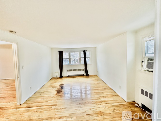 A spacious room with wooden floors and white walls.