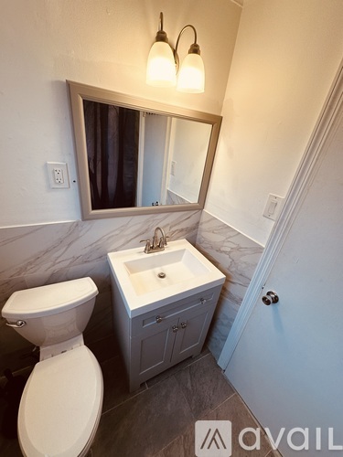 A bathroom with a toilet, sink and mirror.