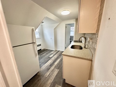 A kitchen with a white refrigerator and wooden flooring.