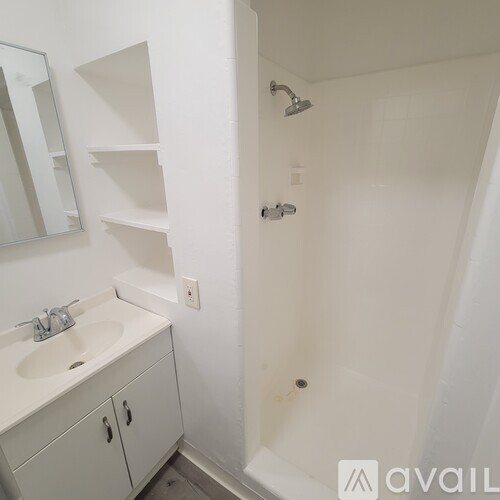 A bathroom with a sink, mirror, and shower.