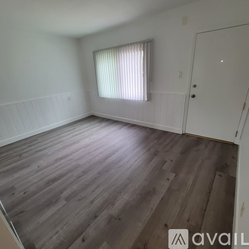 A room with wooden flooring and a window with blinds.