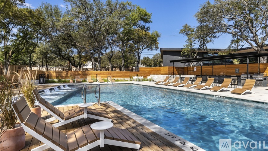 A pool with chairs and a building in the background.
