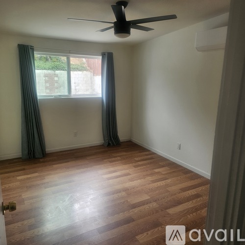 A room with a ceiling fan and wooden flooring.