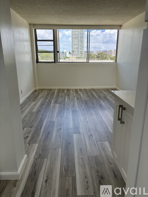 A room with wooden flooring and a view of the city through the window.