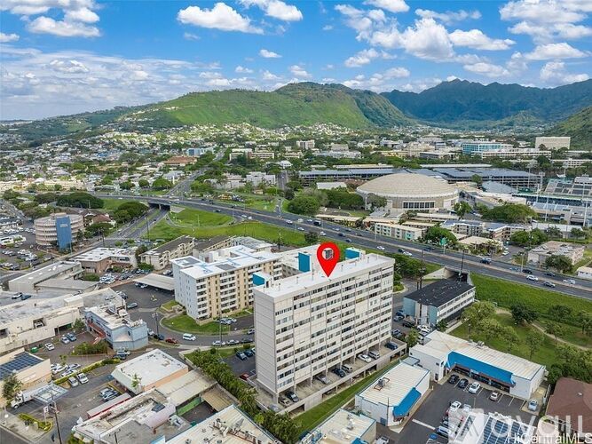 A red pin marks a building in a cityscape with mountains in the background.