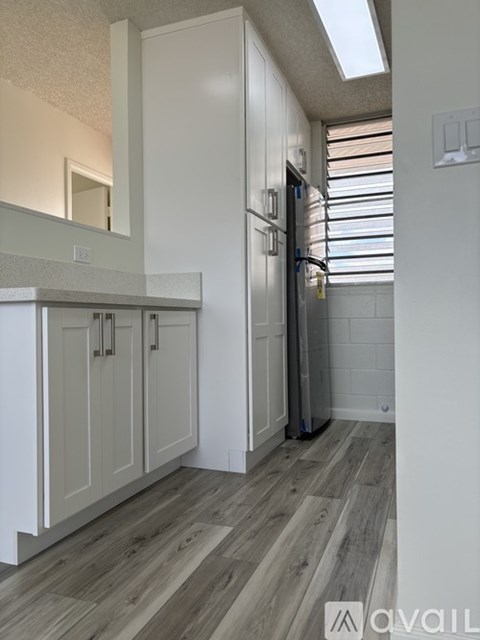 A kitchen with white cabinets and a wooden floor.