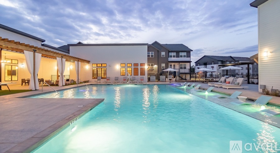 A large outdoor swimming pool with a lit up edge and a building in the background.
